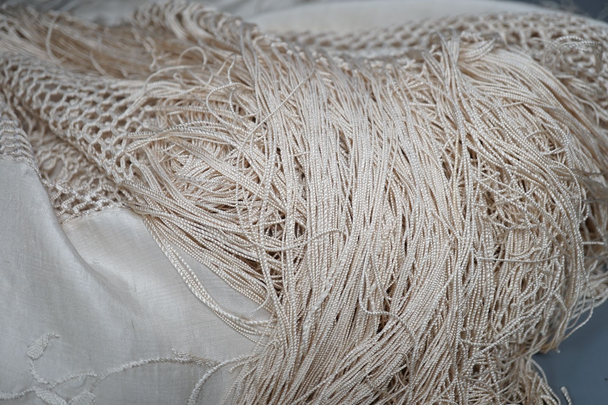 A Chinese cream on cream silk, embroidered shawl with a tasselled fringed edge, 160 cms wide x 160 square.